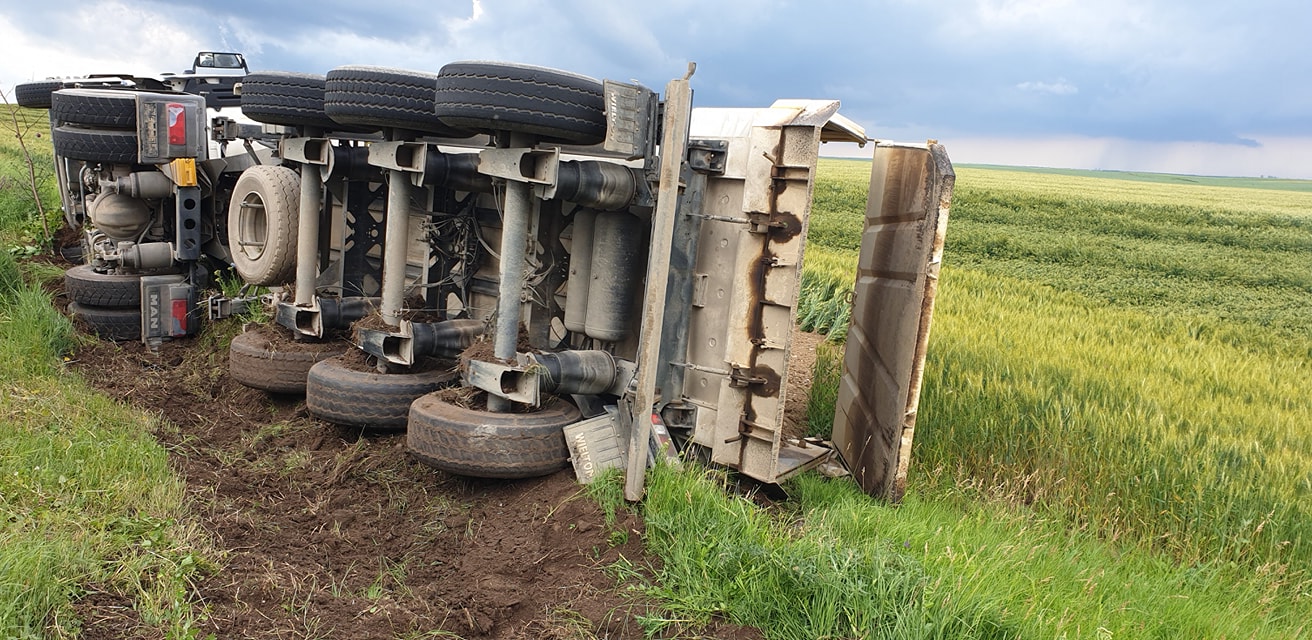 VIDEO Camion cu balast, răsturnat pe un drum din Smeeni. O dubă neagră i-ar fi frânat brusc în față