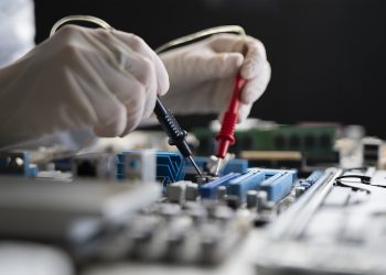 A Person Holding Multimeter Tool And Making Measurement On Pcb Computer Board