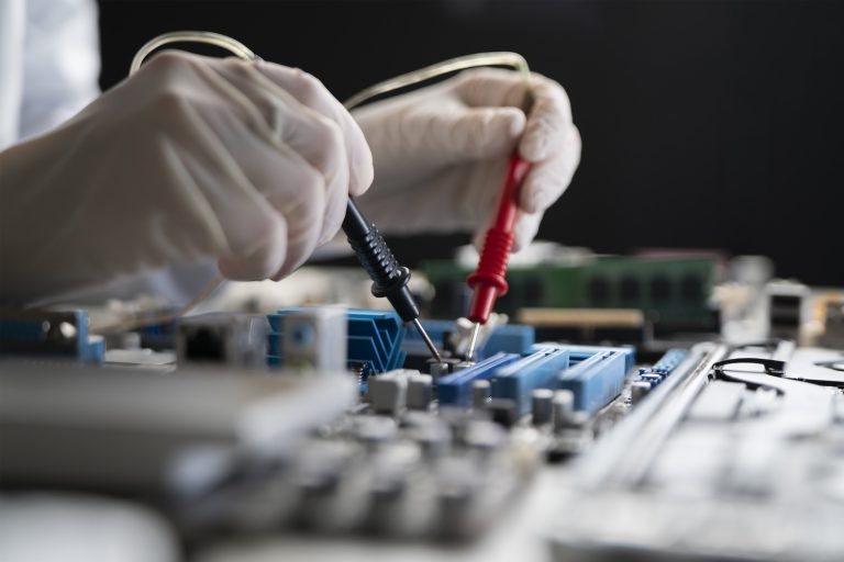 A Person Holding Multimeter Tool And Making Measurement On Pcb Computer Board
